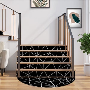 Peut inclure: Des marches d'escalier avec un motif géométrique noir et blanc et un tapis rond assorti. Les marches sont en bois et ont une rampe en métal noir. Le tapis est placé au bas des marches et a une bordure blanche.