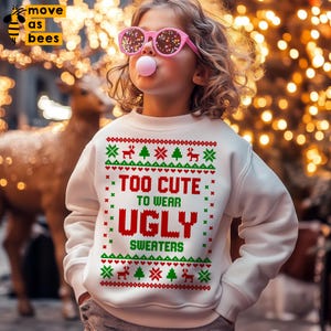 May include: A white Christmas sweater with a red and green design. The sweater has the text "Too Cute To Wear Ugly Sweaters" on it. A young person is wearing the sweater and blowing a pink bubble.