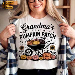 May include: A white t-shirt with the words "Grandma's Pumpkin Patch" in black script. The design includes pumpkins, a wheelbarrow, sunflowers, and names. A fall-themed graphic tee.