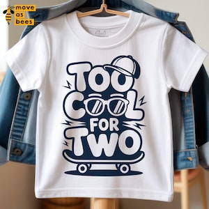 May include: White toddler t-shirt with a navy blue graphic that reads "Too Cool For Two." The design includes sunglasses, a baseball cap, and a skateboard. The shirt is hanging on a hanger.