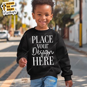 May include: A black sweatshirt with the text "PLACE your Design HERE" in white. A young child is wearing the sweatshirt and blue jeans.