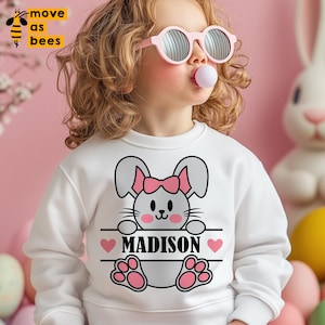 May include: White sweatshirt with a pink bunny rabbit graphic and the name "MADISON" printed on a banner held by the bunny.