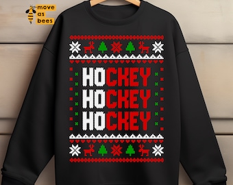 May include: Black sweatshirt with a festive design. The word "HOCKEY" is displayed three times in a vertical stack, with the letters "HO" in white and "CKEY" in red. The design includes snowflakes, reindeer, and Christmas trees in red, green, and white.