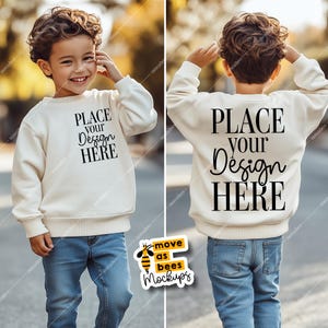 May include: A white sweatshirt mockup for kids with the text "PLACE YOUR DESIGN HERE" on the front and back. The sweatshirt is being worn by a child standing on a sidewalk.