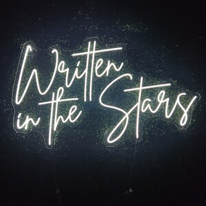 Puede incluir: Letrero de ne&oacute;n blanco con el texto "Written in the Stars" en una fuente cursiva.