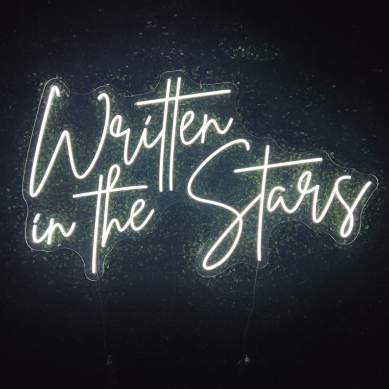 Puede incluir: Letrero de ne&oacute;n blanco con el texto "Written in the Stars" en una fuente cursiva.
