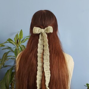 May include: A green crocheted bow tied in a woman's long brown hair.