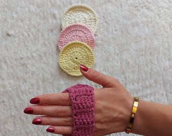 Peut inclure: Quatre ronds en coton crochetés en blanc, rose et jaune empilés les uns sur les autres. Une main portant un bracelet de poignet en crochet rose avec un bracelet en or.