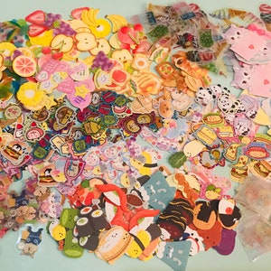 May include: A large collection of colorful stickers featuring various themes, including food, animals, and cute characters. The stickers are perfect for decorating journals, planners, and other craft projects.