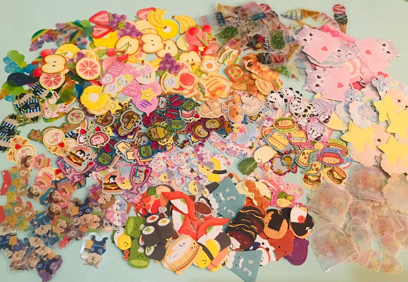 May include: A large collection of colorful stickers featuring various themes, including food, animals, and cute characters. The stickers are perfect for decorating journals, planners, and other craft projects.