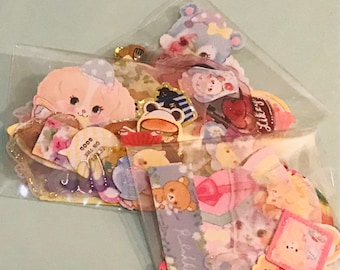 Puede incluir: Una bolsa de plástico transparente llena de pegatinas coloridas con animales de dibujos animados, corazones y diseños florales. Las pegatinas son de varios tamaños y formas, algunas con texto como "Good on the Go" y "Sticky".