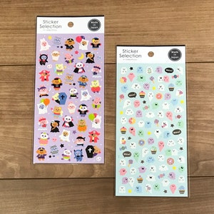 May include: Two rectangular sheets of stickers labeled Sticker Selection and Made in Japan. The left sheet is purple with various costumed animal characters. The right sheet is light blue with small ghosts, cupcakes, and candies.