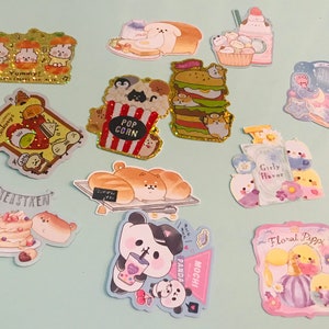 May include: A collection of colorful stickers featuring cute animal characters and various themes, including bakery, popcorn, panda, and floral. The stickers are perfect for adding a touch of whimsy to journals, planners, and other creative projects.