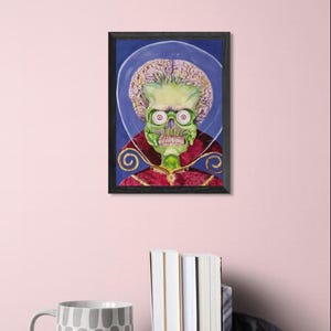 May include: A framed portrait of a green-skinned alien with large red eyes, a skeletal face, and a large brain. The alien is wearing a red and gold robe against a blue background. The artwork is in a black frame.