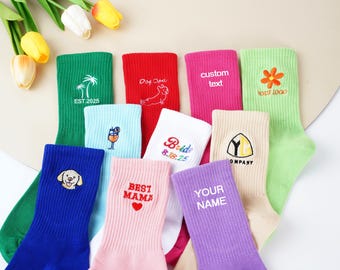 Puede incluir: Calcetines coloridos variados con diseños y texto bordados. Los diseños incluyen una palmera, un perro, un cóctel, una flor y las palabras "Dog Dad", "Best Mama", "Bride", "Your Name" y "Custom Text".