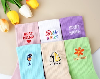 Puede incluir: Calcetines coloridos variados con diseños y texto bordados. Los calcetines incluyen las frases "BEST MAMA", "Bride 8.18.25" y "YOUR NAME". Otros calcetines presentan un cóctel, una flor y un logotipo de empresa.