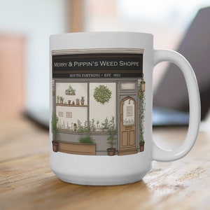 May include: White ceramic mug with a black and white illustration of a shop front. The shop is called "Merry & Pippin's Weed Shoppe" and is located in "South Farthing - Est. 2021".