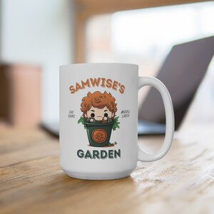 May include: White ceramic mug with a cartoon illustration of Samwise Gamgee from The Lord of the Rings. The text "Samwise's Garden" is printed on the mug. The text "The Shire" and "Middle Earth" are printed on the sides of the mug.
