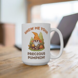 May include: White ceramic mug with a cartoon illustration of a wizard holding a pumpkin. The text on the mug reads "Show me your precious pumpkin!"