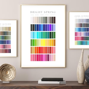 Puede incluir: Tres impresiones enmarcadas de paletas de colores con marcos dorados. Las impresiones están etiquetadas como "Soft Autumn", "Bright Spring" y "Cool Summer". La impresión "Bright Spring" tiene una amplia gama de colores, incluyendo azules, verdes y rosas.