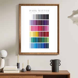 May include: A framed color palette chart labeled "Dark Winter" with rows of various colors. The color swatches include shades of gray, purple, pink, yellow, teal, and blue. The frame is a warm brown color.