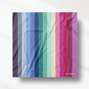 Puede incluir: Una muestra de tela cuadrada con un patrón de rayas verticales en un degradado de colores que incluye morado, azul, verde, amarillo y rosa. La tela tiene una textura suave y plegada, con el texto COOL SUMMER impreso en blanco en la esquina.