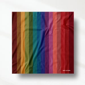 Puede incluir: Una muestra de tela cuadrada con un patrón de rayas verticales en un degradado de colores otoñales profundos que incluyen marrón, dorado, verde oliva, azul verdoso, azul, morado, magenta, coral y rojo oscuro, con el texto DEEP AUTUMN abajo a la derecha.