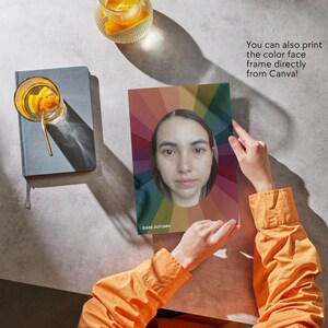 May include: A person holds a color palette with a woman's face in the center. The palette has a rainbow design with the text "Dark Autumn" at the bottom. The text "You can also print the color face frame directly from Canva!" is visible in the background.