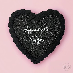 May include: Black heart-shaped cake with black glitter frosting and white lettering that says "Aquarius Szn".