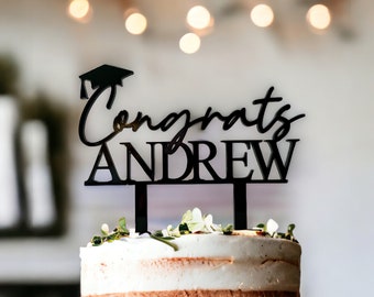 May include: Black acrylic cake topper with a graduation cap, the word "Congrats" and the name "Andrew".