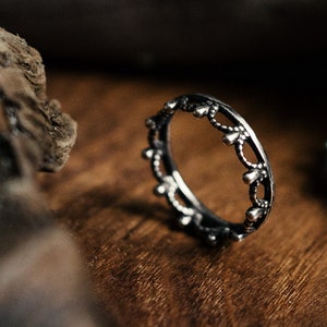 Può includere: Tre anelli d'argento con un designo decorativo. Gli anelli sono su una superficie di legno.