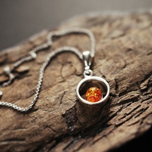 Minimalist and delicate amber pendant. Sterling silver and natural Baltic amber. Circle with amber pearl. Dainty gem. For everyday wear.