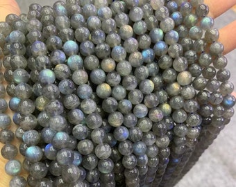May include: A strand of round, gray labradorite beads with iridescent blue and green flashes. The beads are approximately 8mm in diameter.