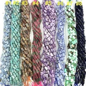 May include: Eight strands of gemstone beads, each strand is labelled with a number from 1 to 8. The beads are all rectangular and have a variety of colours, including green, brown, pink, purple, blue, and black.