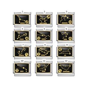 Könnte beinhalten: Eine Sammlung von zwölf rechteckigen Anhängern, die jeweils ein anderes Sternbild in Gold auf schwarzem Hintergrund zeigen. Die Anhänger sind in einem silberfarbenen Metallrahmen gefasst, mit dem Namen des Sternzeichens darunter.