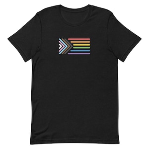 May include: Black t-shirt with a multi-colored graphic of a progress pride flag. The flag is made up of six stripes, each a different color: brown, light brown, yellow, orange, pink, and light blue.