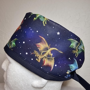 May include: A blue surgical scrub hat with a tie. The hat has a repeating pattern of dragons flying in a starry night sky.