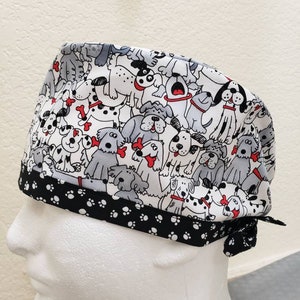 May include: A white and black scrub hat with a pattern of cartoon dogs. The hat has a black and white paw print trim.
