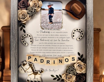 May include: A framed shadow box with a photo of a child wearing a cowboy hat, surrounded by paper flowers, horseshoes, and the word "PADRINOS". The text in the frame reads "Ser Padrinos es ser segundos papás" and "De Bautizo?"