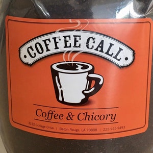 May include: A white resealable bag filled with dark brown coffee and chicory grounds. The bag has a red and orange label with the text "Coffee Call" and "Coffee & Chicory". The label also includes the address "3122 College Drive, Baton Rouge, LA 70808" and the phone number "225 925 9493".