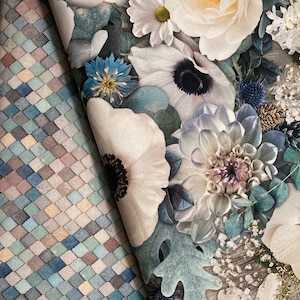 K&ouml;nnte beinhalten: Nahaufnahme eines Blumenstoffes mit einem Muster aus wei&szlig;en, blauen und gr&uuml;nen Blumen. Der Stoff hat eine strukturierte, fast gesteppte Optik.