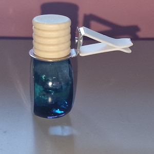 May include: A blue glass car air freshener with a wooden top and a white clip.