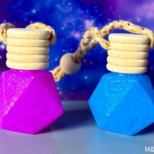 May include: Two geometric car air fresheners, one magenta and one blue, with wooden tops and braided cords. The background is a galaxy design. The text "M&D SCENTS" is visible in the bottom right corner.