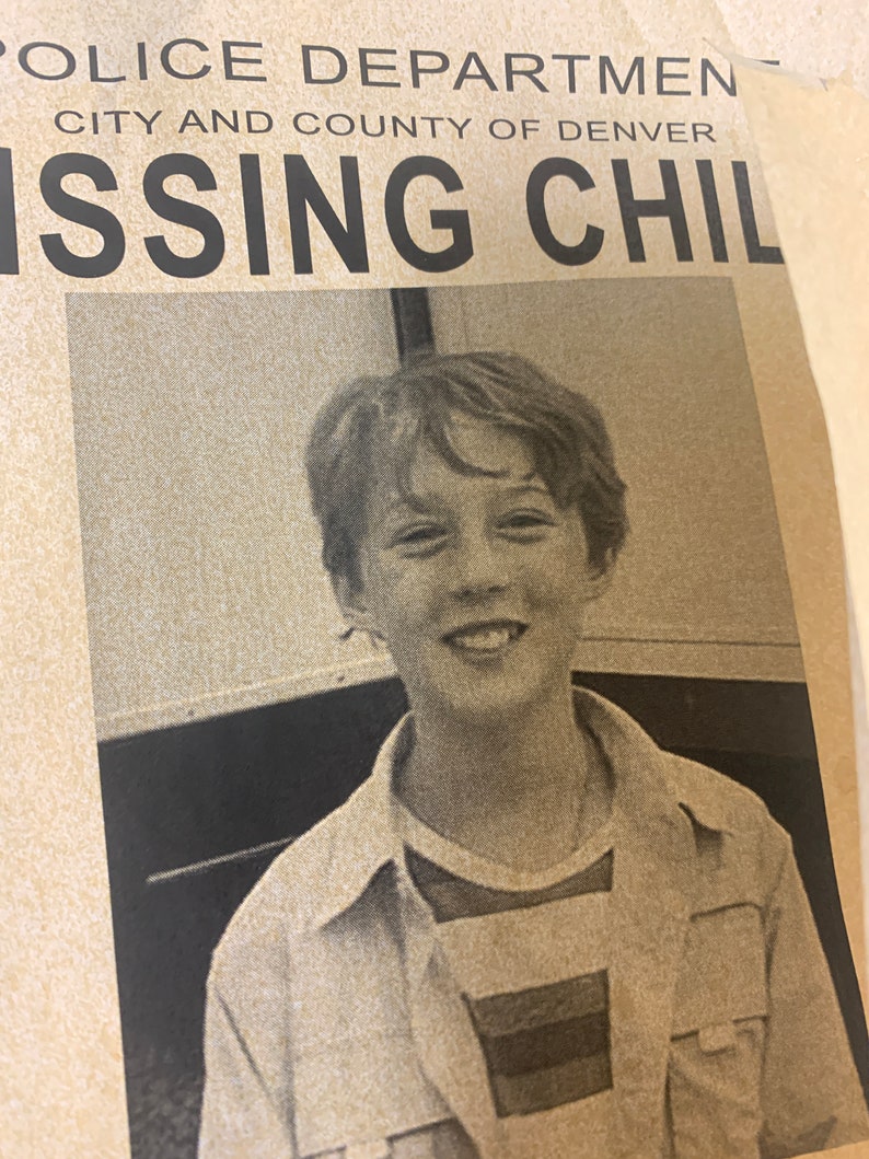 May include: A black and white photo of a young boy with short brown hair. He is wearing a striped shirt and a light brown jacket. The photo is from a missing child poster. The poster reads "Police Department City and County of Denver Missing Child".