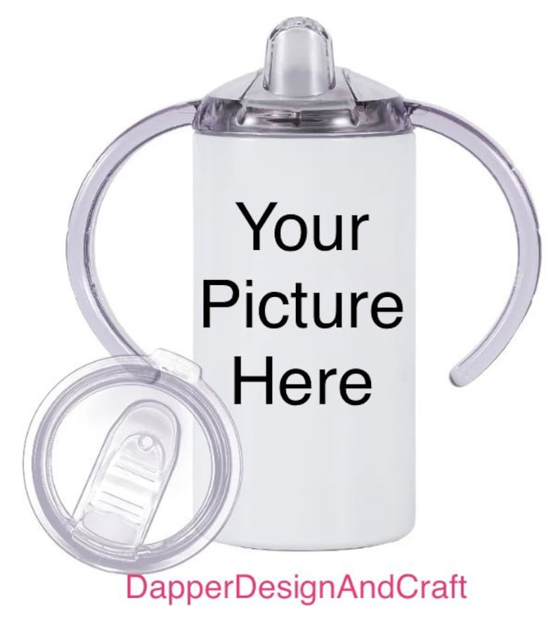 Puede incluir: Un vaso de acero inoxidable blanco con dos asas de pl&aacute;stico transparente y una tapa de pl&aacute;stico transparente. El vaso tiene el texto "Your Picture Here" impreso en &eacute;l.