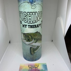 May include: A stainless steel tumbler with a blue and green design. The tumbler features a largemouth bass and the text "Fishing is my therapy".