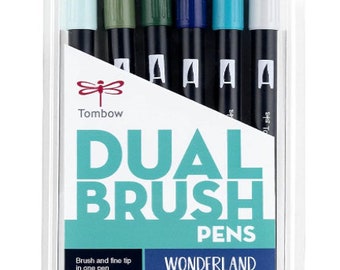 May include: A set of six Tombow Dual Brush Pens in a clear plastic package. The pens are labeled "Wonderland" and feature a winter scene with a house and a tree. The text "Let It Snow" is printed below the image. The pens have a brush tip and a fine tip.
