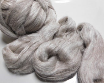 May include: A pile of light brown and white alpaca fiber. The fiber is soft and fluffy, and it is perfect for spinning or felting.