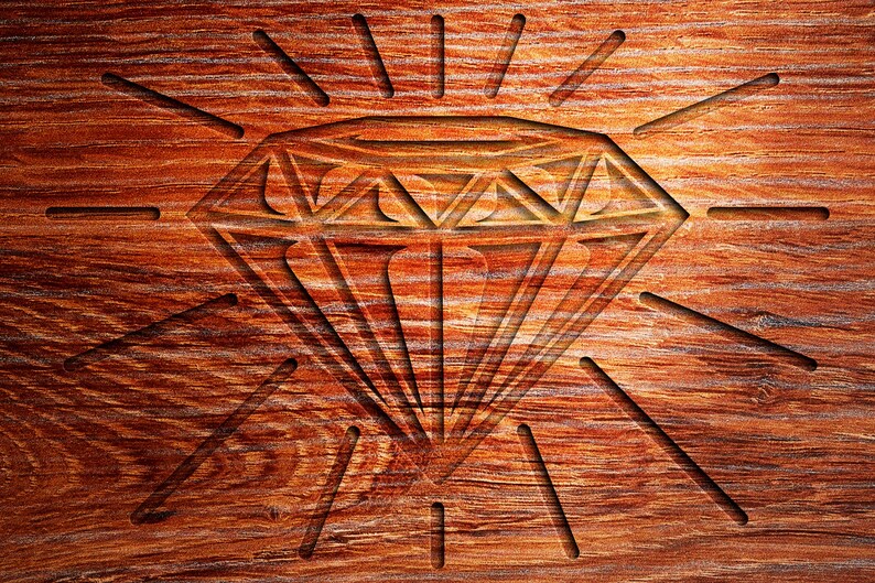 May include: A diamond shape carved into a piece of wood with a sunburst pattern radiating out from the diamond.