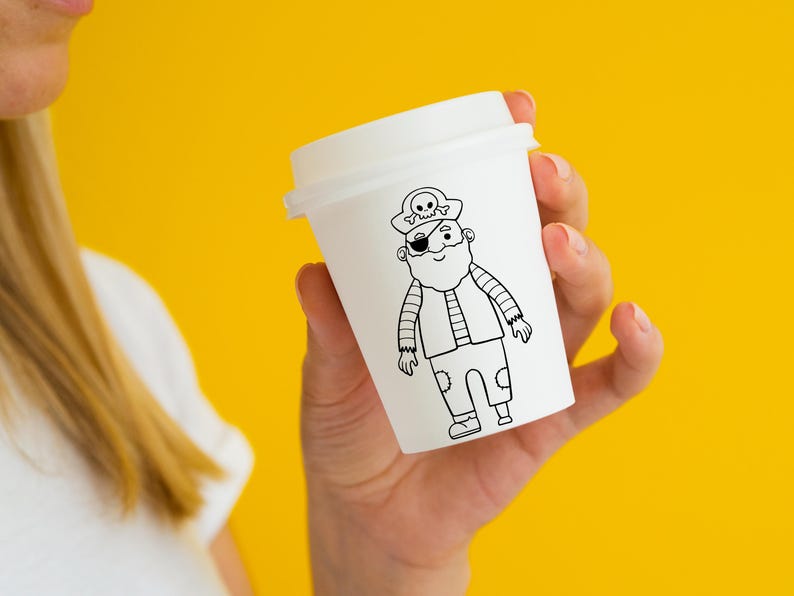 May include: A white paper cup with a black and white illustration of a pirate wearing an eye patch and a hat with a skull and crossbones.